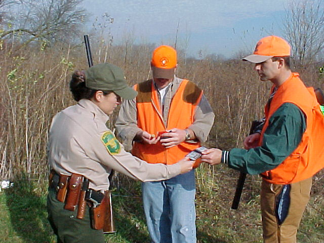 A Conservation Police officer talking with hunters in the field